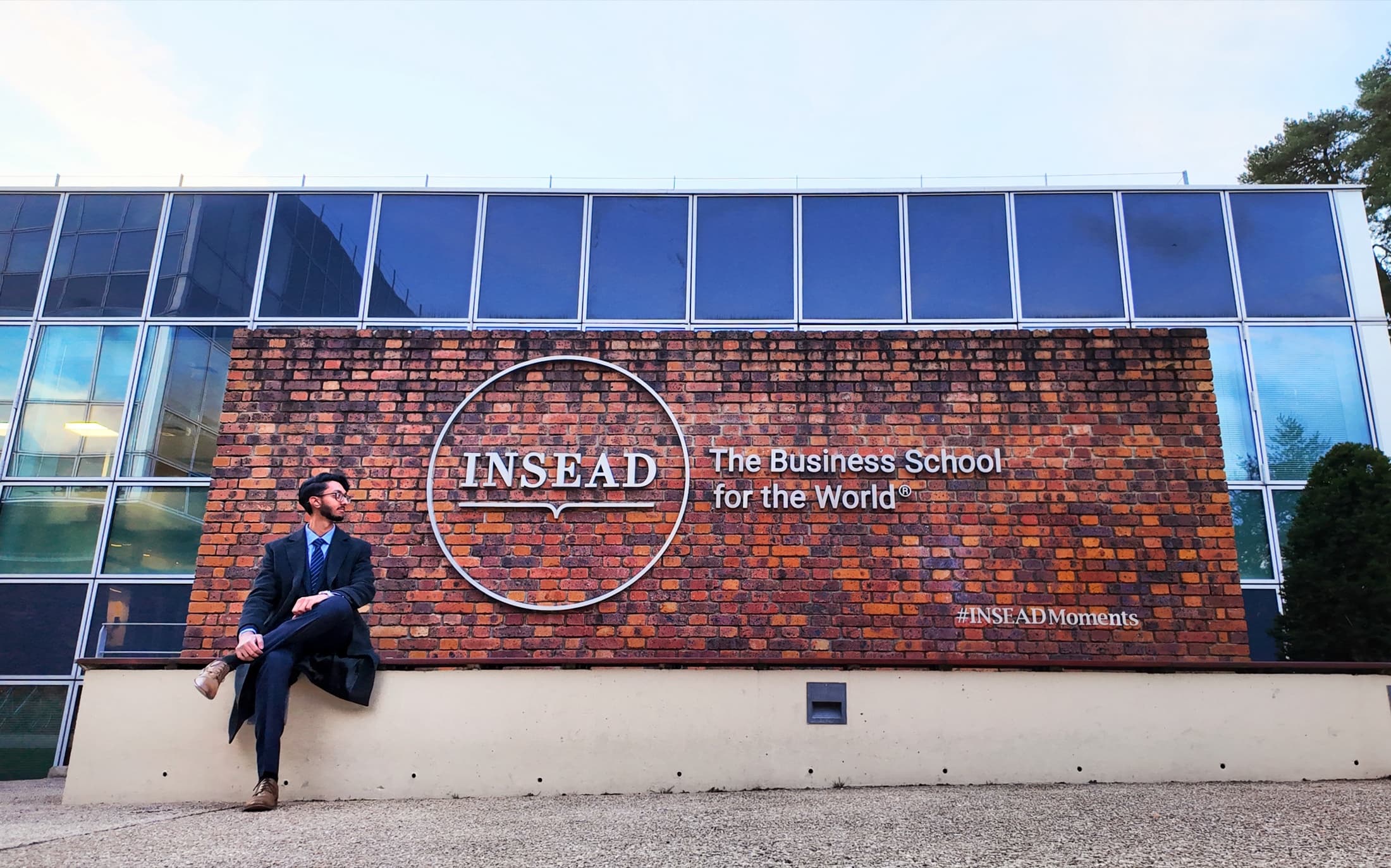 Kai Kaushik at INSEAD, Fontainebleau Kai Kaushik, INSEAD MBA, sitting in front of the INSEAD sign on the Fontainebleau campus
